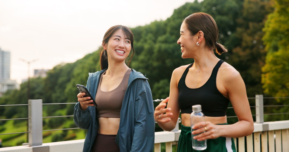 Two female athletes having a conversation on a bridge.