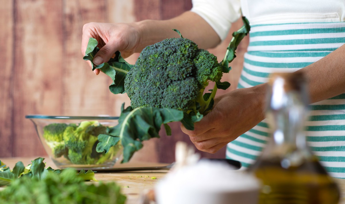 A cook preparing a dish of broccoli.
