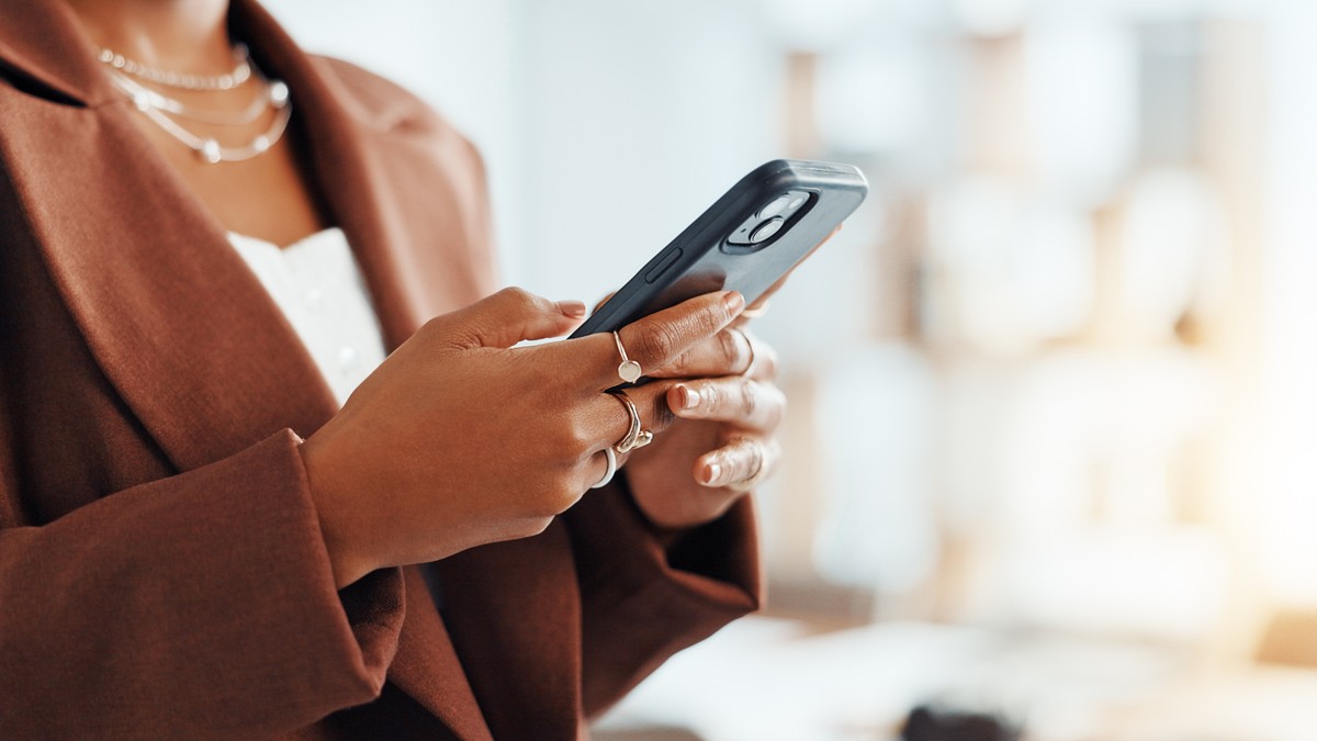 Hand holding a smartphone, possibly texting or browsing.