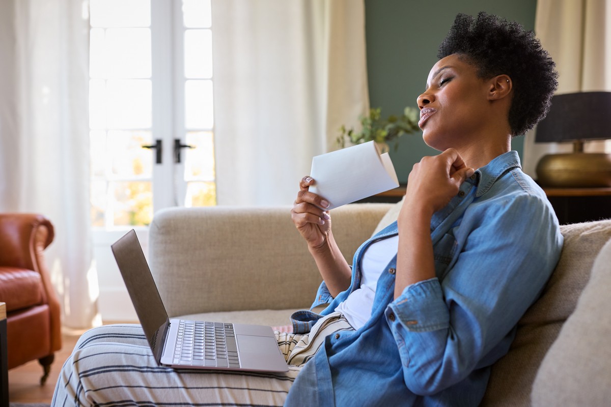 Person in denim shirt using laptop and reading mail.
