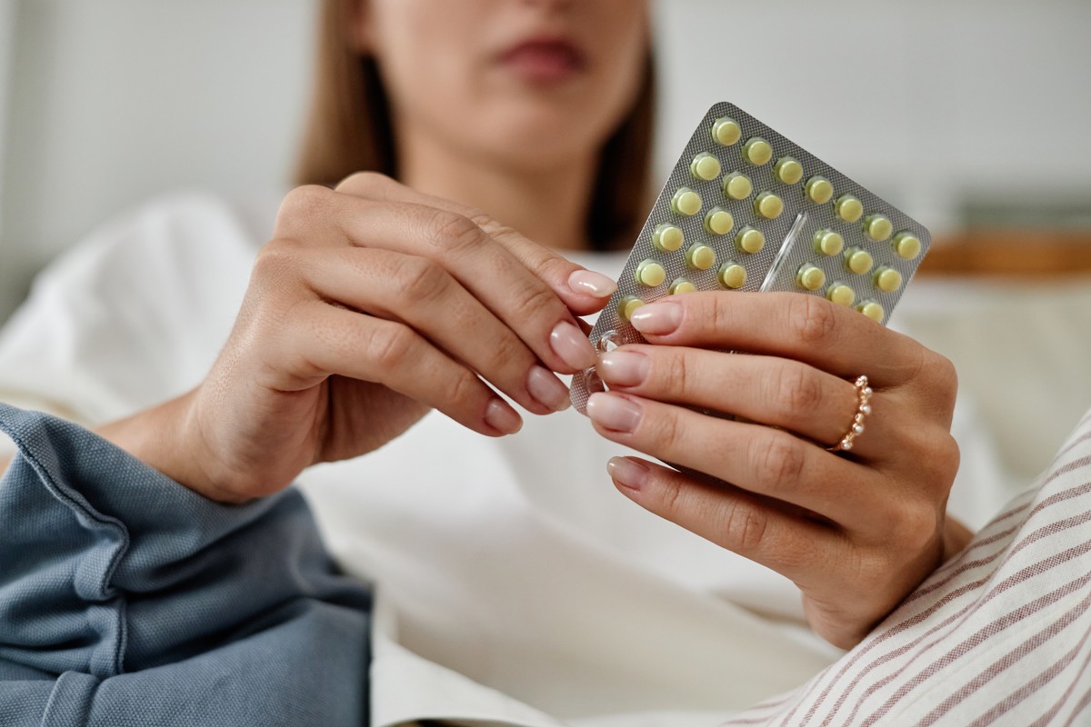 Pregnant woman holding a blister pack of pills.