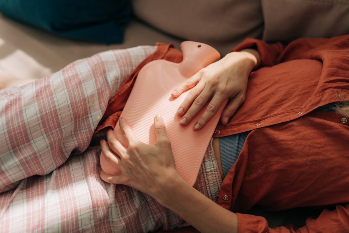 A woman lying down, her hand on her stomach, with a surprised or perhaps exhausted expression.