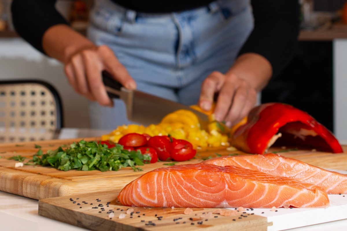 A person preparing seafood with ingredients on a cutting board.