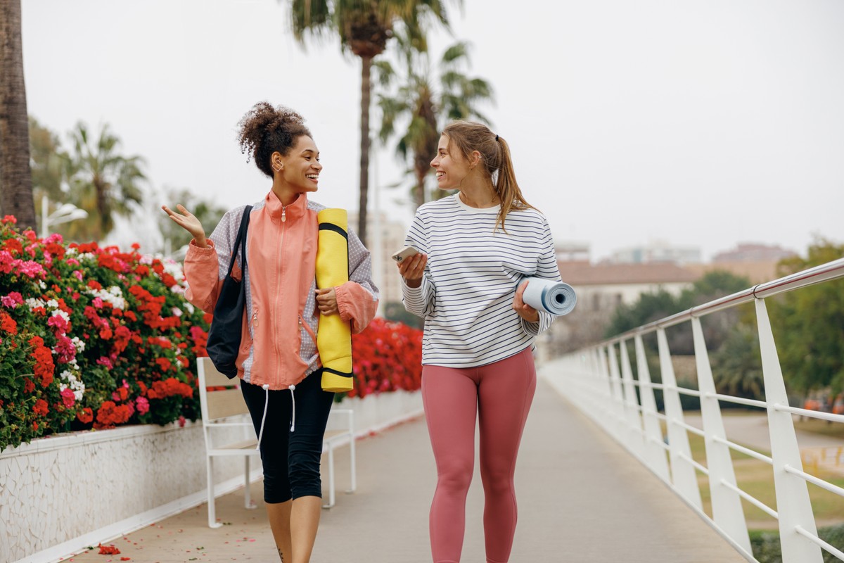 Two women walking outdoors, one smiling towards the other.