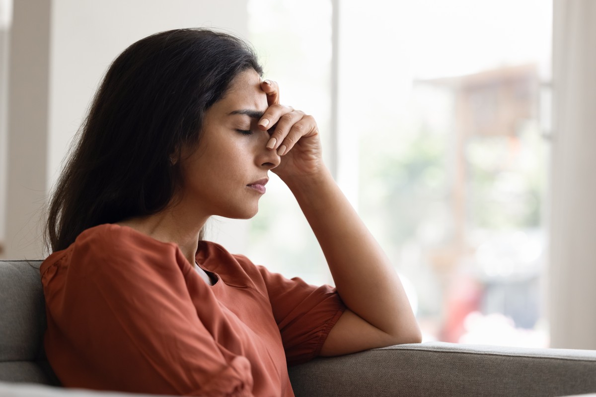 Woman with hand on face, looking out a window.