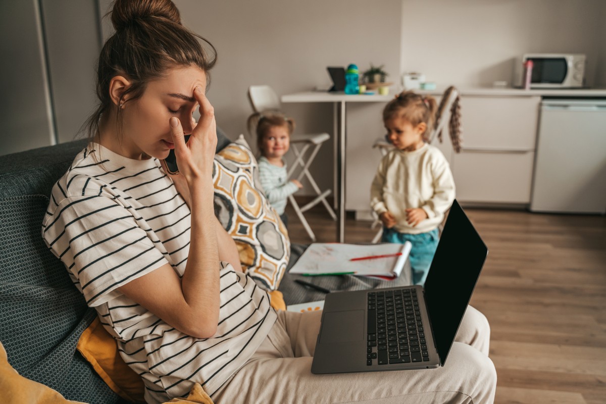 Woman using laptop with baby sitting in front of her.