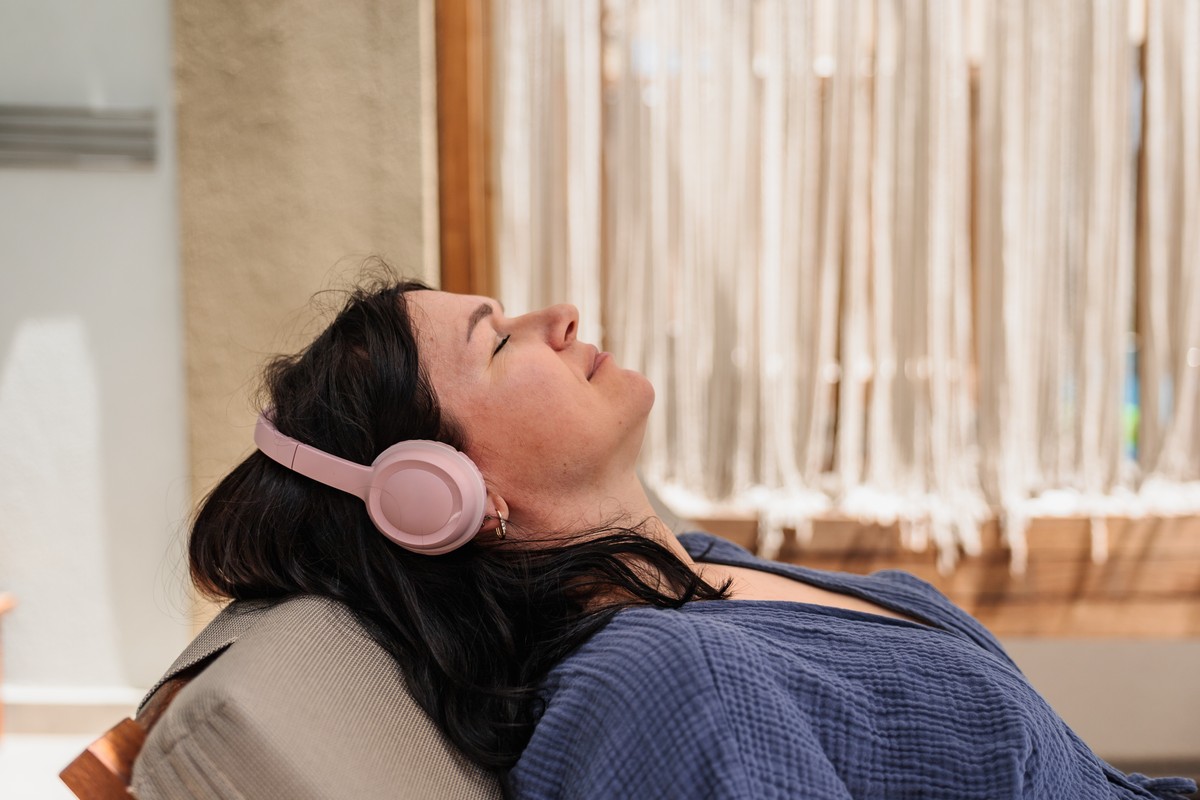 A woman reclined with pink headphones, seemingly sleeping or resting.