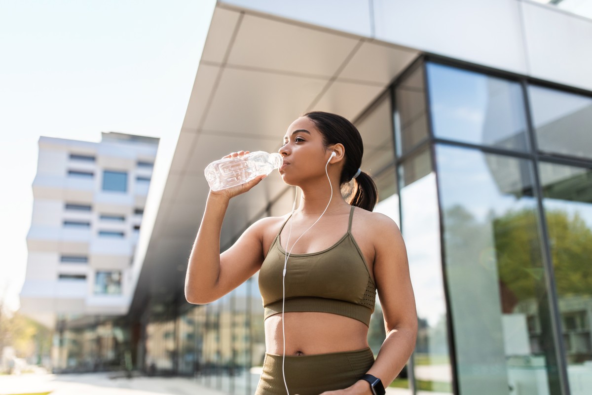 Woman in sports bra holding water bottle.