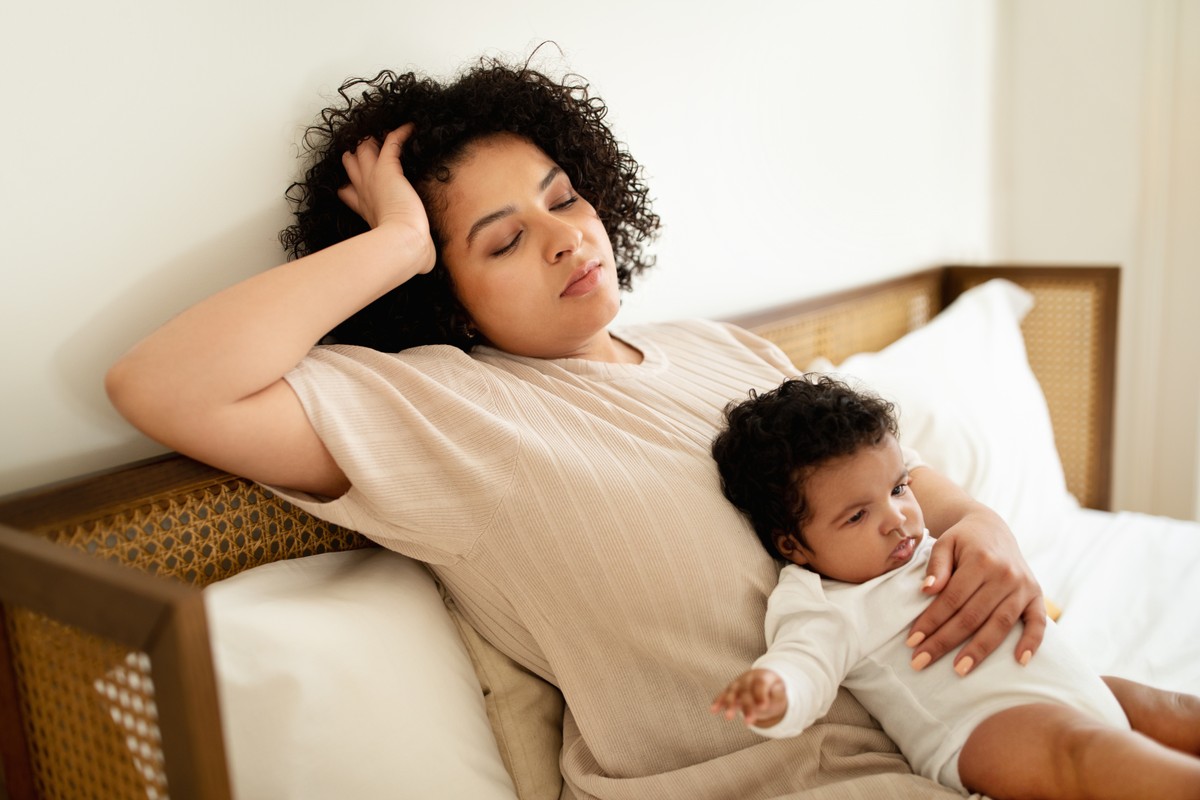 Woman nursing baby, resting in bed.