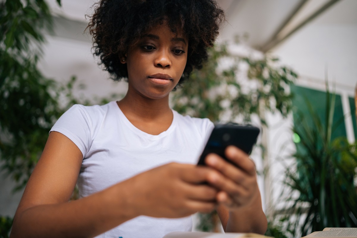 A young woman holding a smartphone, engrossed in her screen.