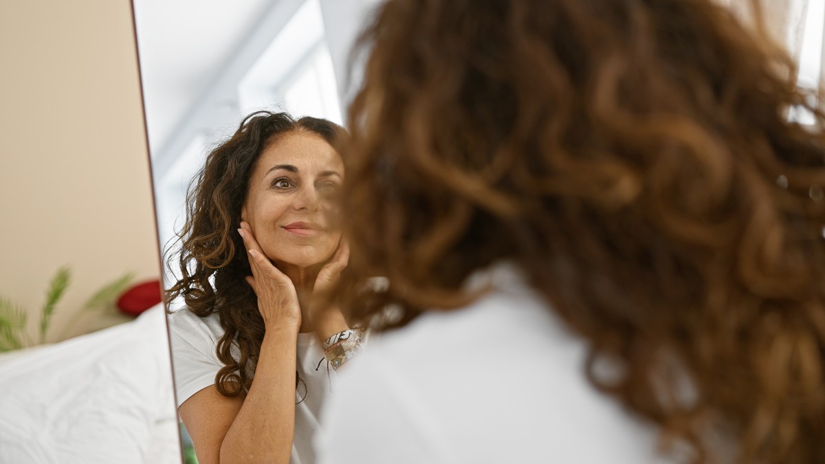 Woman looking at her reflection in the mirror.