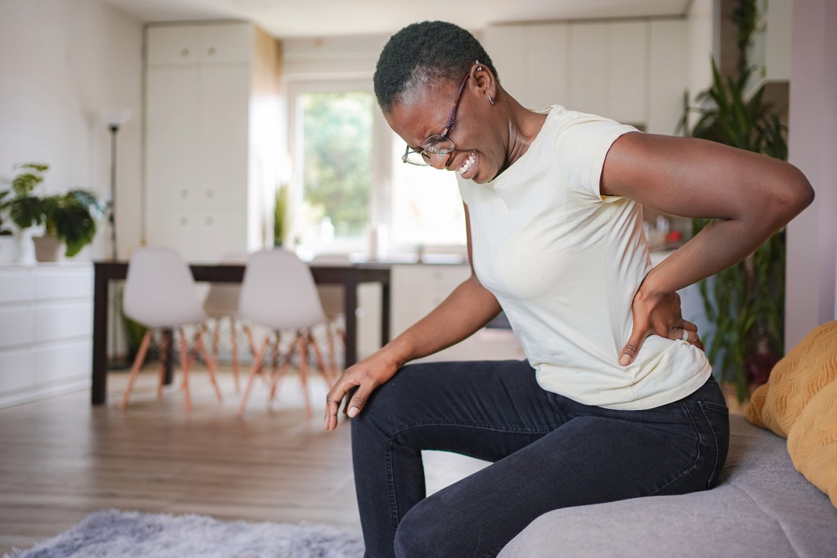 Woman kneeling on a cushion, exercising her knee in a living room.