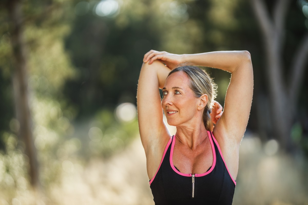Person in athletic attire stretching outdoors.