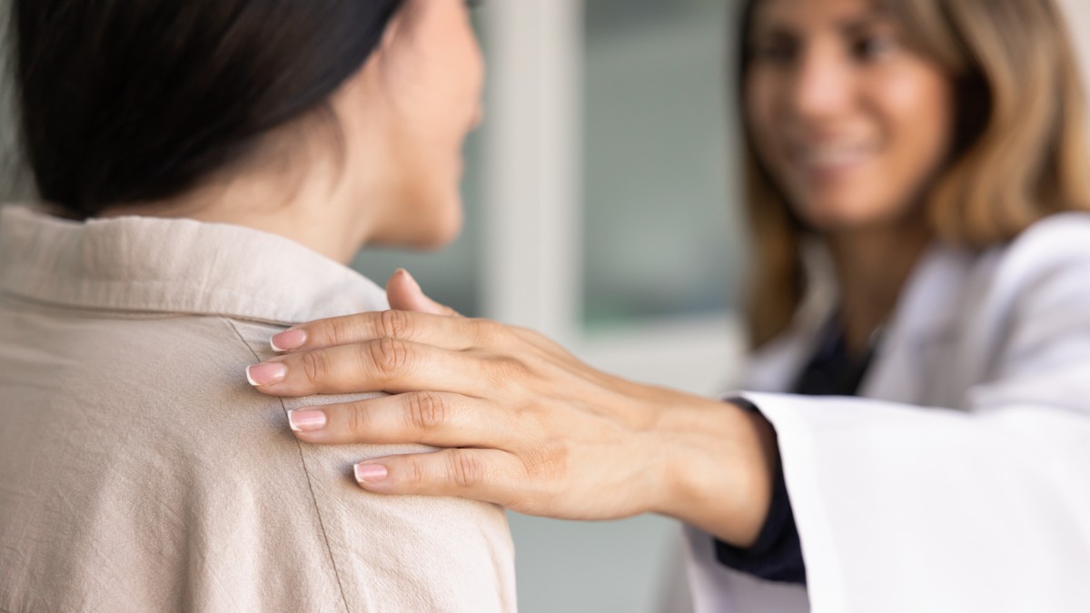 Chiropractic care professional assisting a female patient with her back.