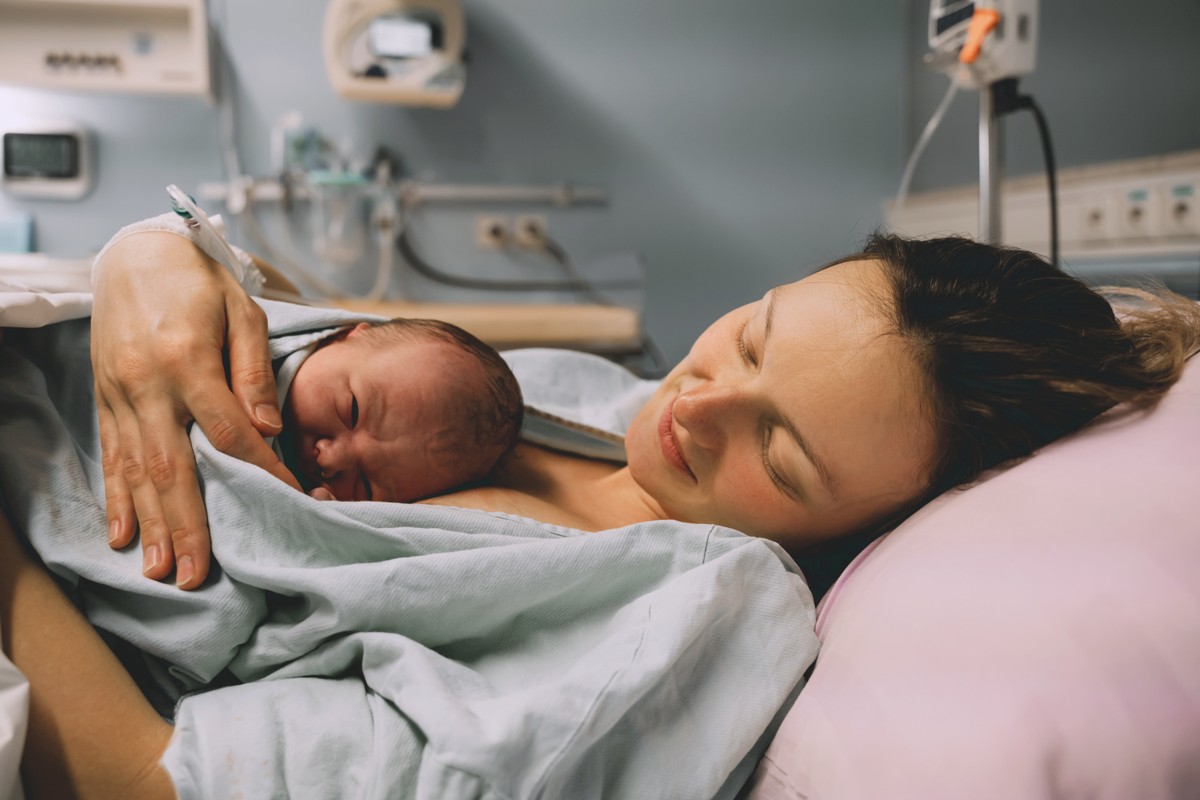 Mother in maternity ward holding newborn baby.