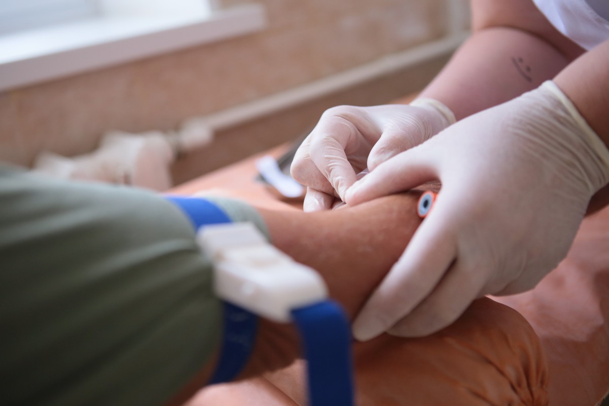 Healthcare worker administering a medication to a patient in a clinical setting.