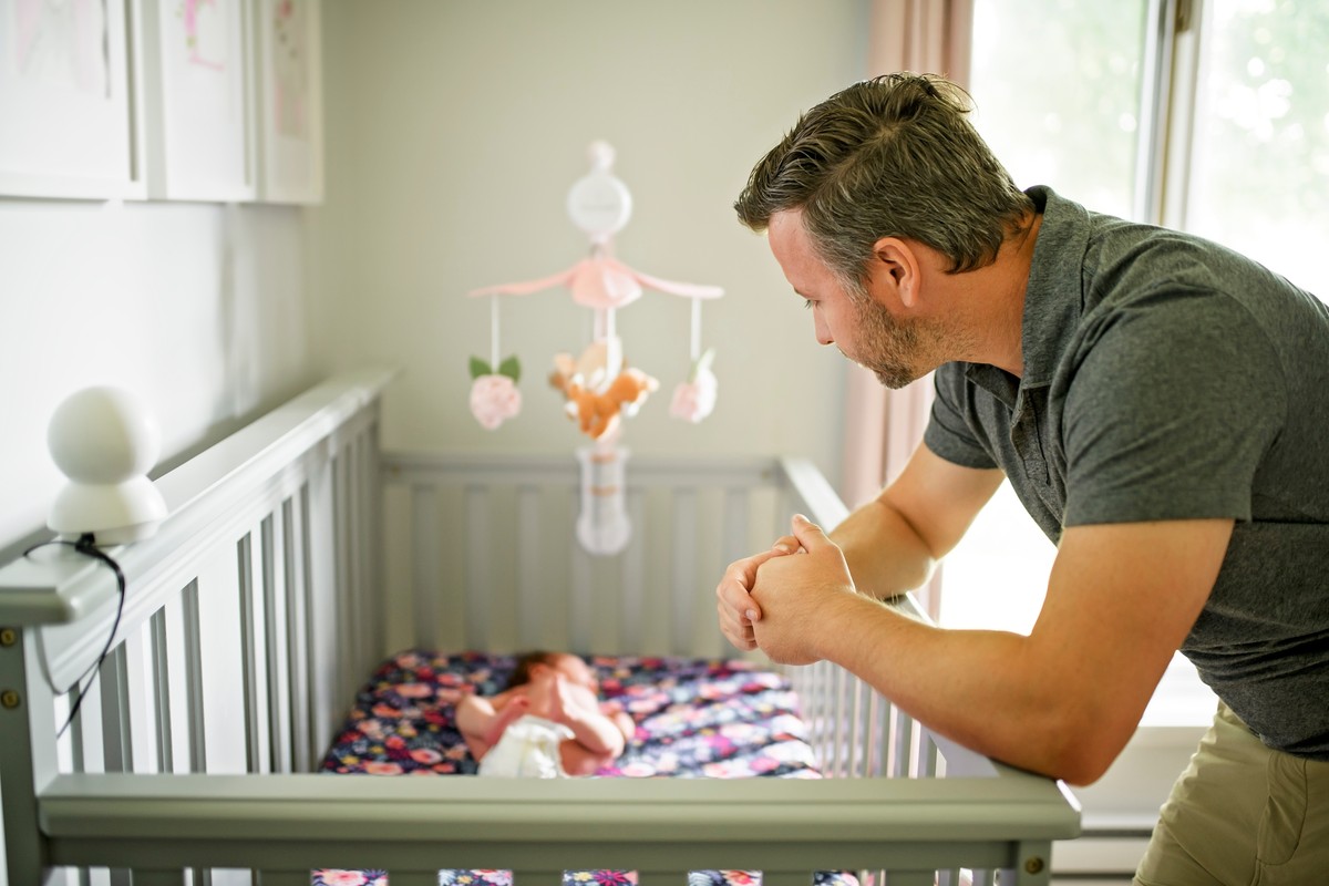 Man tending to newborn in crib, looking down at baby.