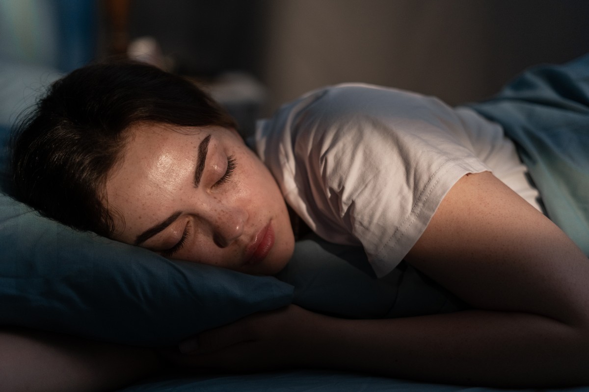 Sleeping girl with eyes closed, in a dimly lit room.